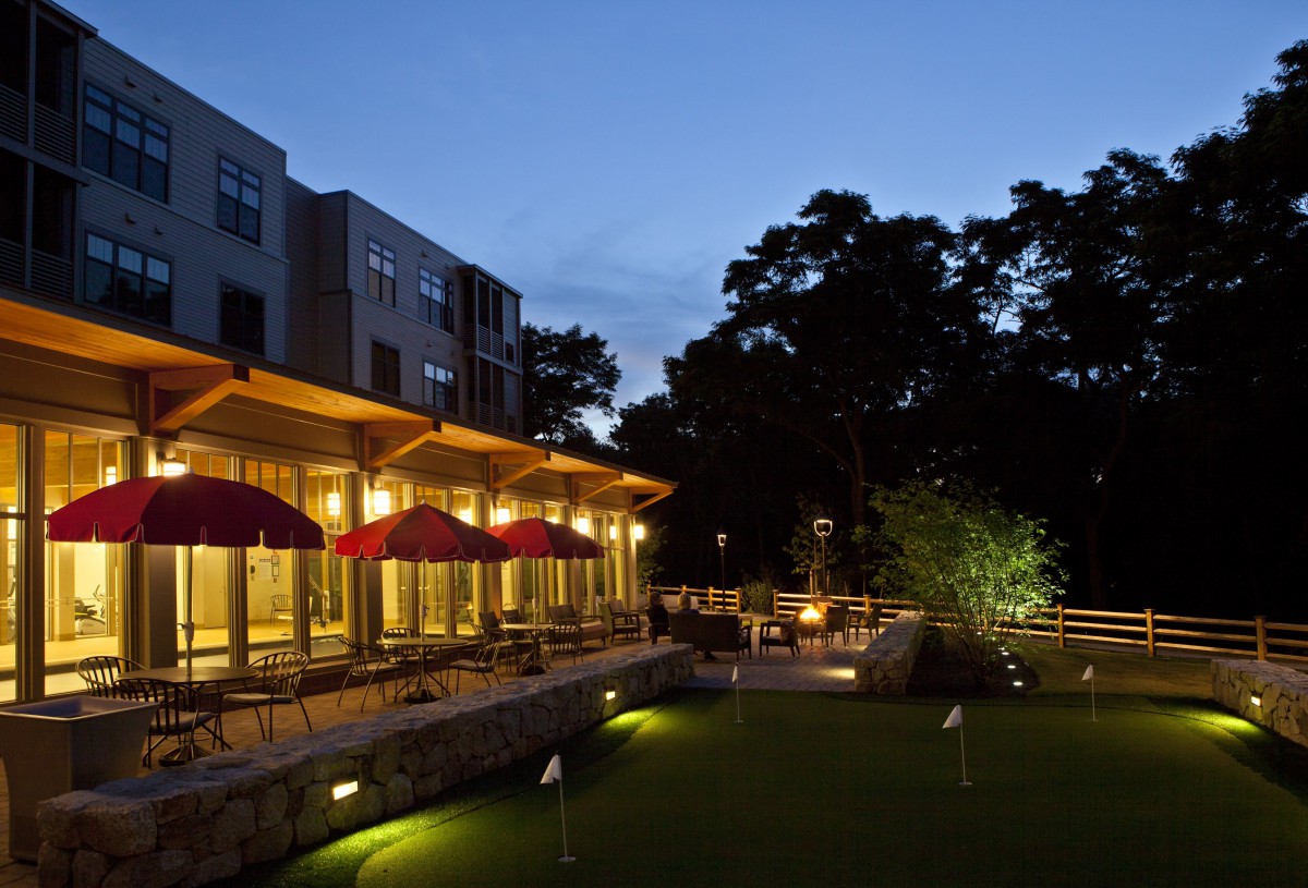 An outdoor restaurant patio lit up in the evening, surrounded by trees.