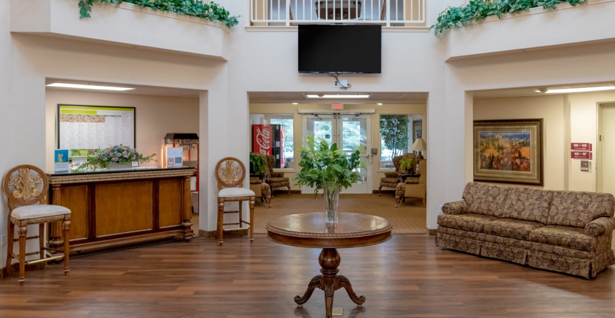 A well-furnished lobby with a central table decorated with plants, surrounded by comfortable seating and a reception area.