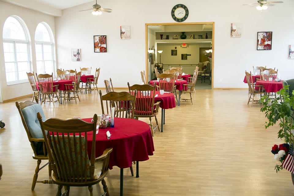 A spacious restaurant dining room with tables covered in red tablecloths.