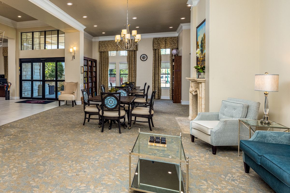 A spacious and elegantly designed living area featuring a dining table, comfortable seating, and a decorative chandelier.