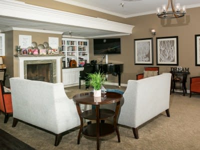 A cozy living room with a fireplace, two sofas, and a grand piano.