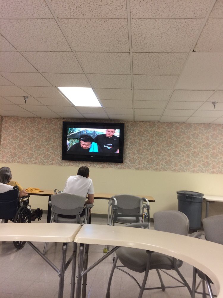 Two people watching television in a communal seating area.