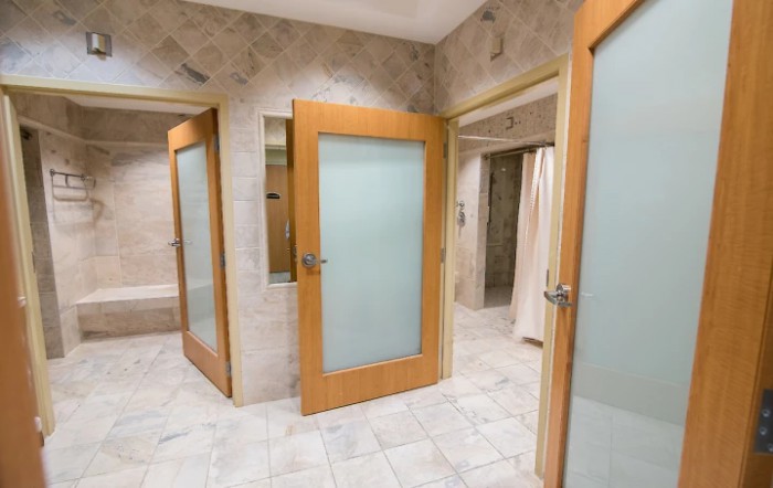 A modern bathroom with multiple shower stalls and frosted glass doors.