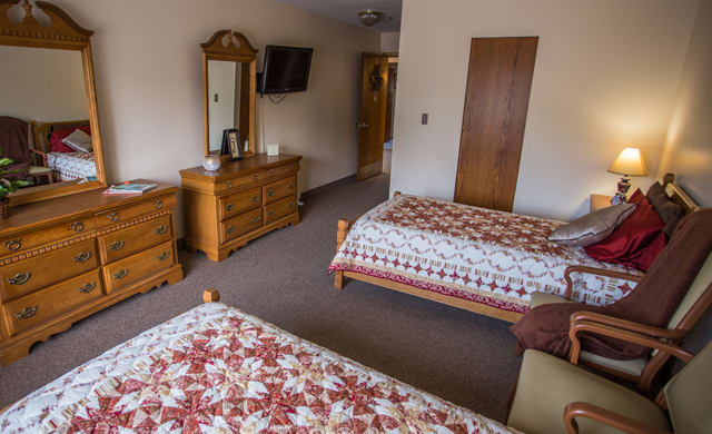 A cozy hotel room with two double beds and wooden furniture.