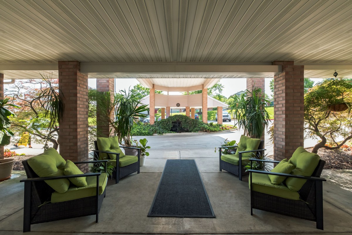 A covered entrance with comfortable seating and lush greenery welcomes visitors.
