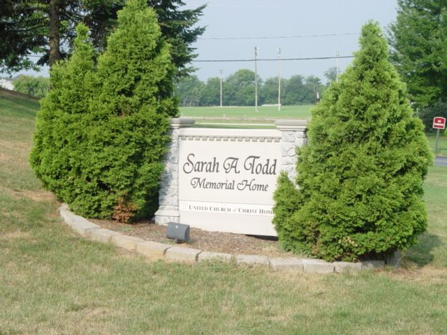 Stone memorial sign among trees in an outdoor setting.