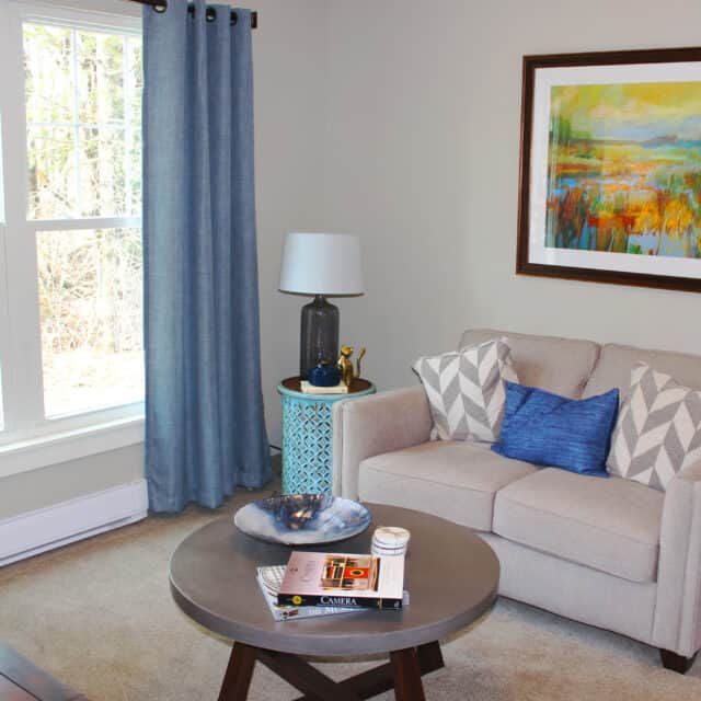 A cozy living room with a beige sofa, blue accents, and modern decor.