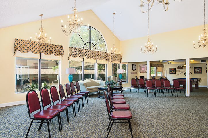 A well-lit conference room with arranged chairs and elegant chandeliers.