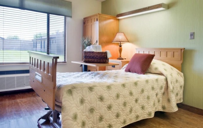 A cozy bedroom with a neatly made bed and a wooden desk by the window.