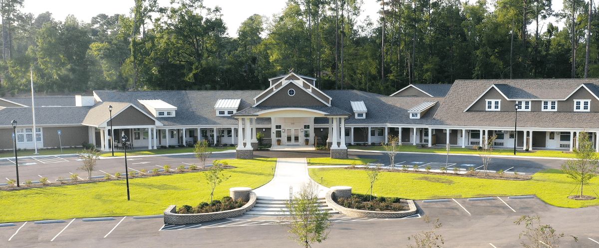 A symmetrical building with a landscaped entrance and surrounding greenery.