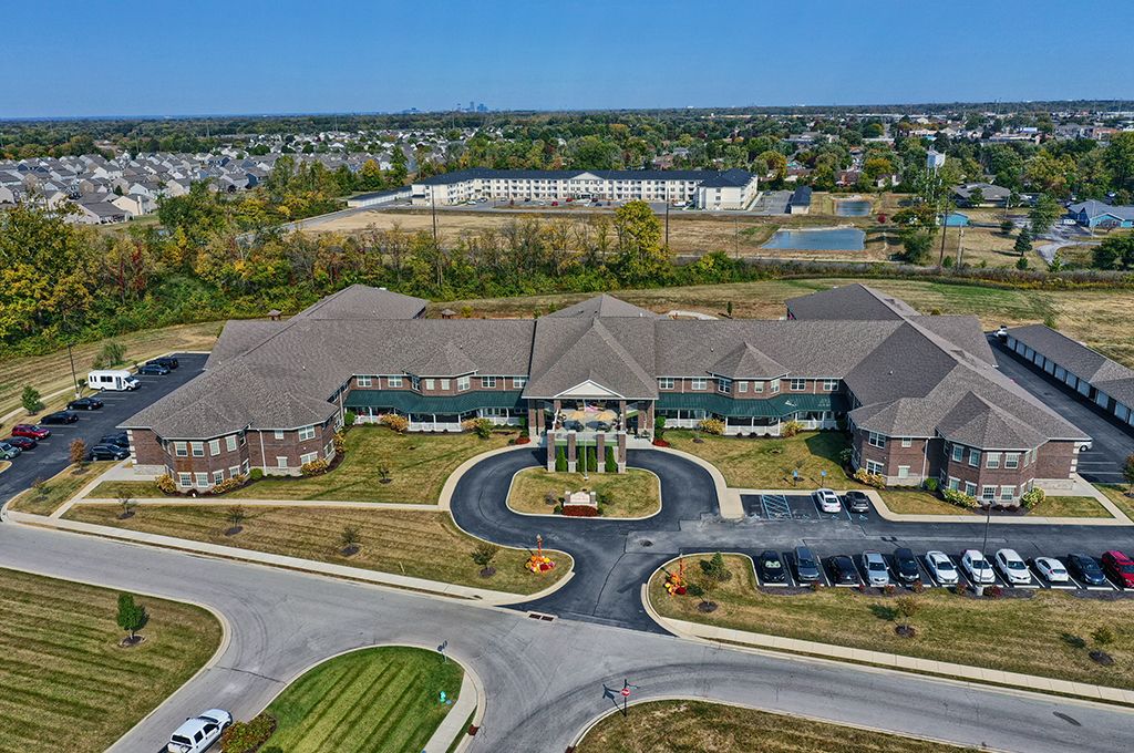 Aerial view of a large building with a circular driveway and parking lot in a suburban area.
