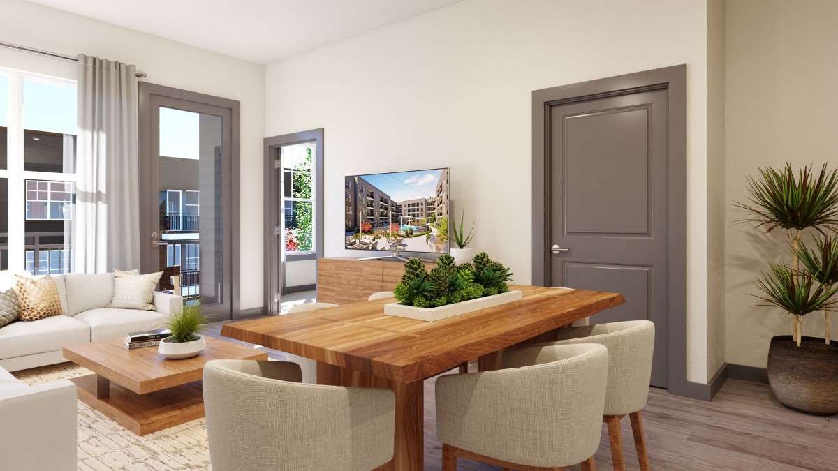 A modern dining room with a wooden table and upholstered chairs, featuring decorative plants and bright lighting.