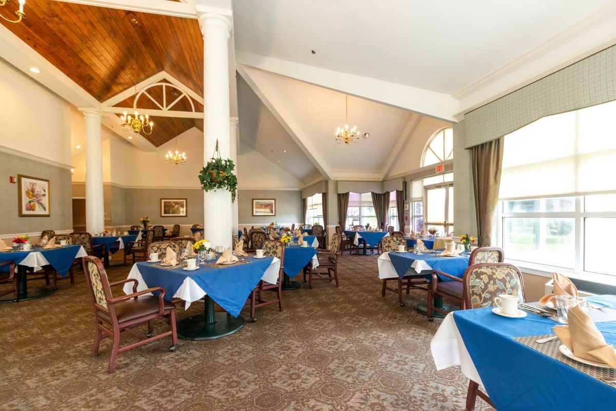 A spacious dining room with blue tablecloths and elegant decor.