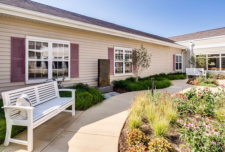 A well-maintained garden area with a bench and pathway in front of a building.