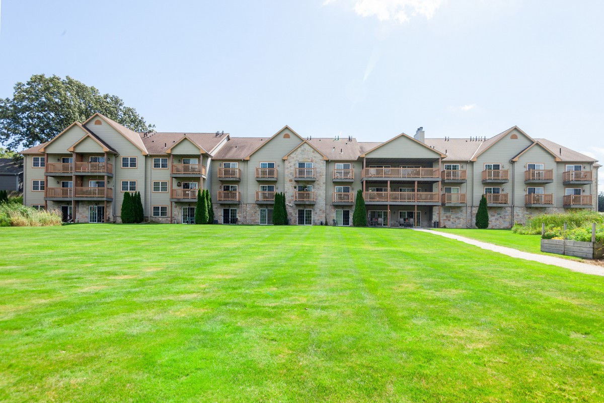 A large residential apartment building with a well-maintained green lawn in front.