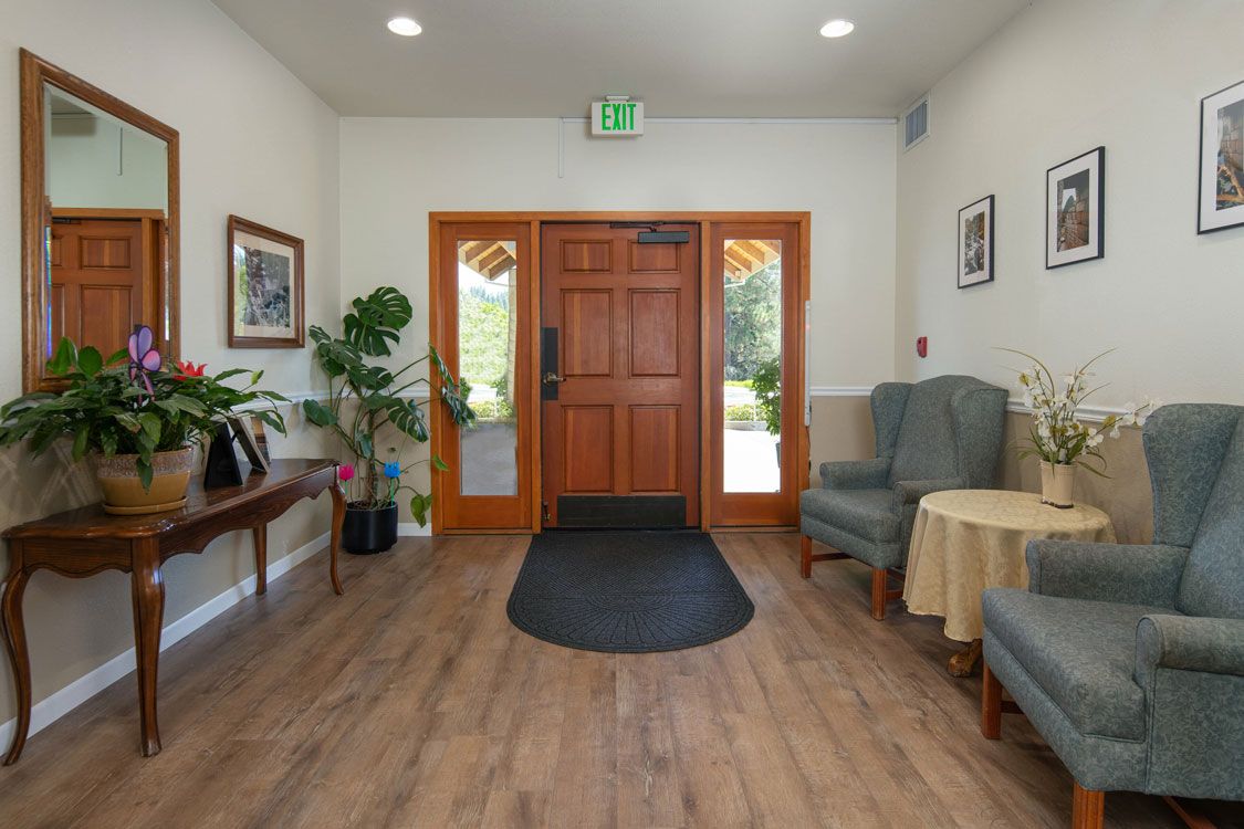 A welcoming entrance with wooden flooring, plants, and comfortable seating.