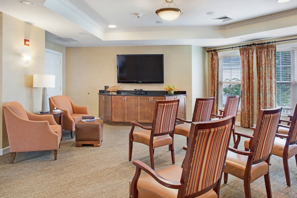 A comfortable lounge area with chairs arranged around a television, featuring modern interior design.