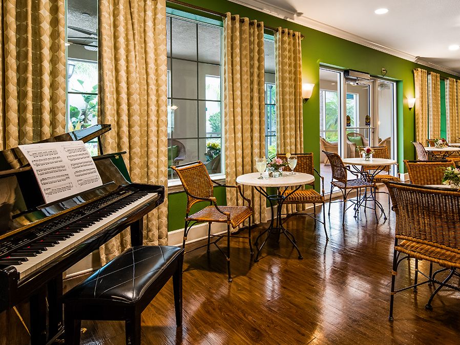 A cozy dining area with a piano, featuring green walls and elegant curtains.