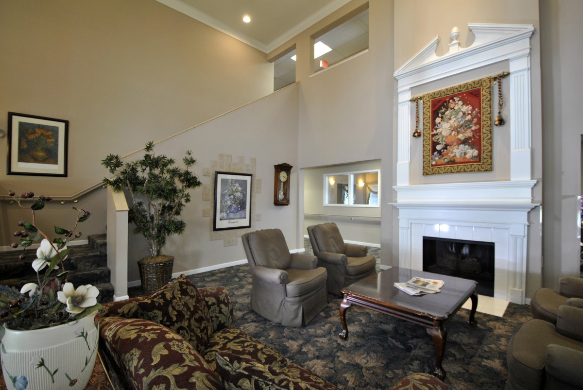 A spacious living room with high ceilings, featuring comfortable seating, a fireplace, and decorative artwork on the walls.