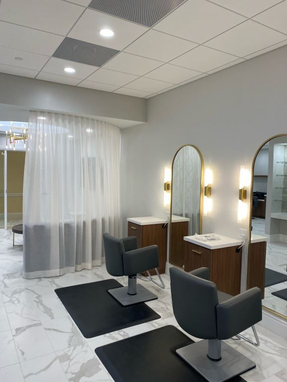 A modern salon interior with stylish chairs, mirrors, and soft lighting.
