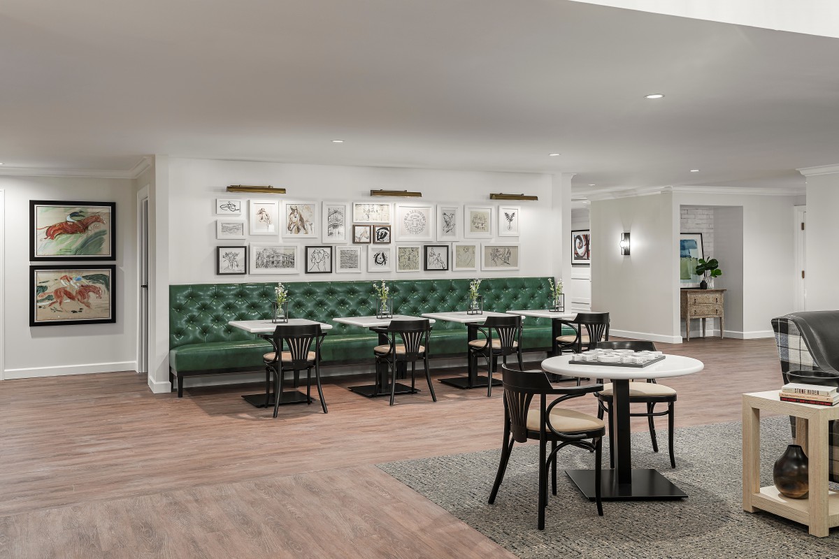 A modern restaurant interior featuring green upholstered seating, artistic wall decor, and stylish dining tables and chairs.