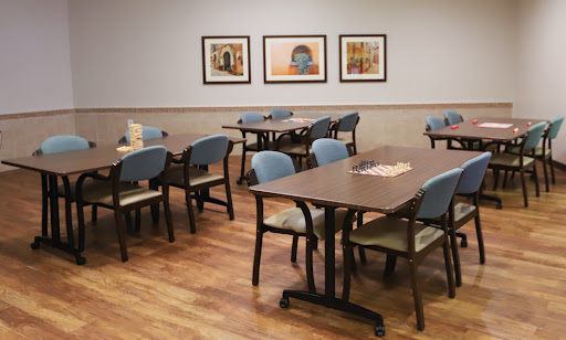 A casual dining area featuring neatly arranged tables and chairs, adorned with artworks on the walls.