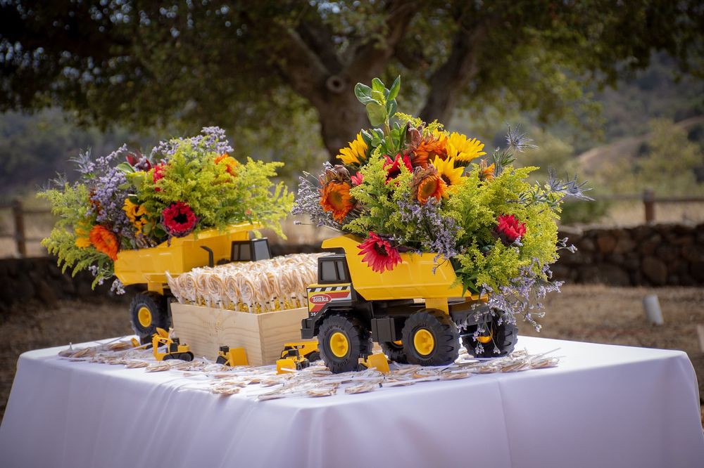 Toy trucks creatively used as vases for vibrant flowers in an outdoor table setting.