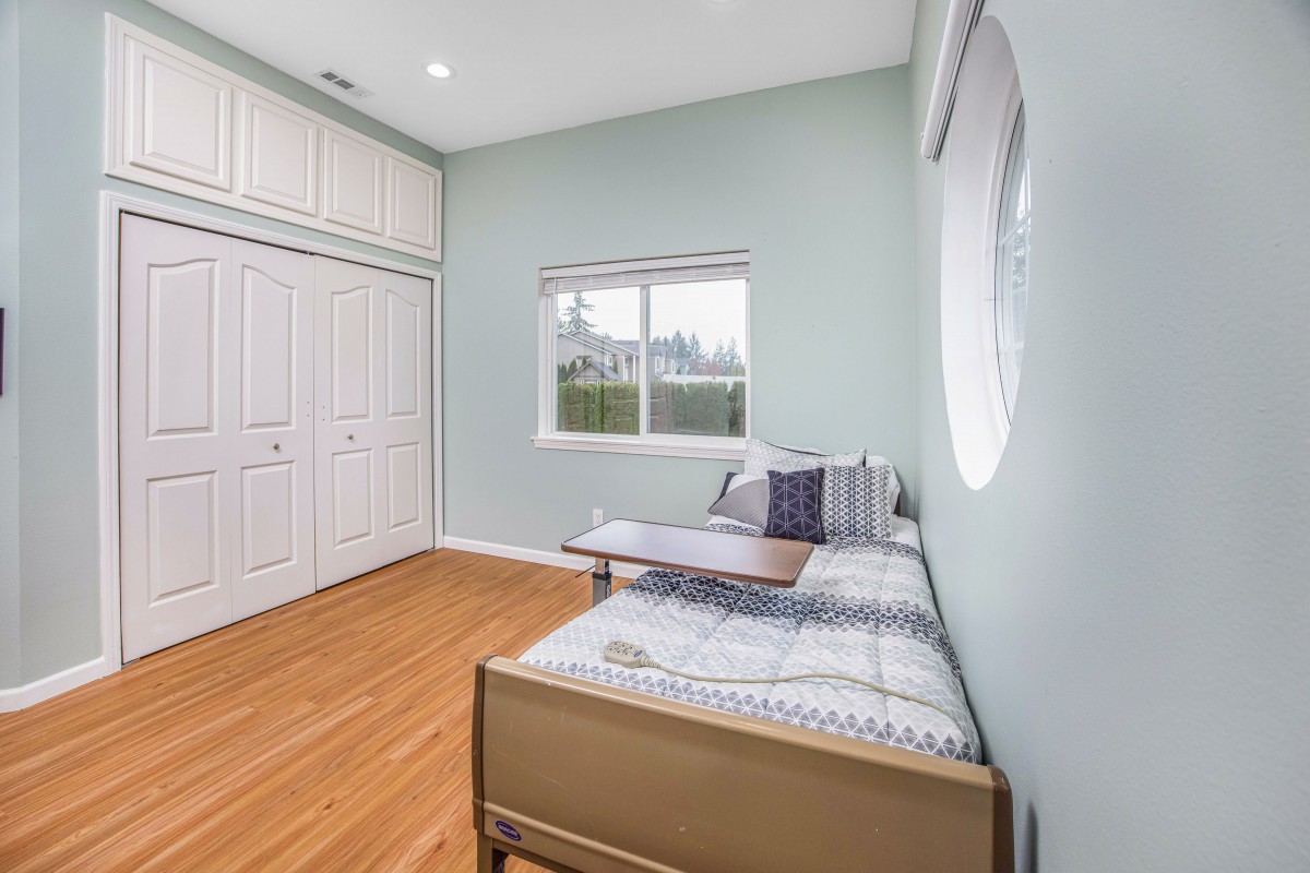 A minimalist bedroom featuring a single bed, large closet, and hardwood flooring.
