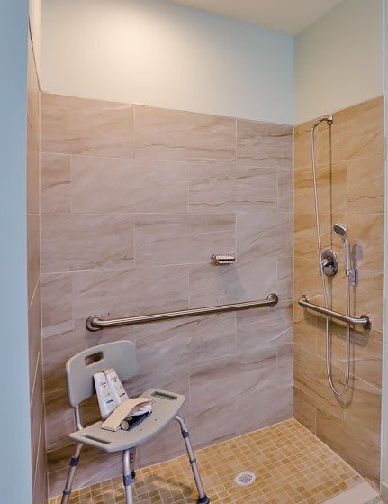 An accessible walk-in shower featuring a shower chair and grab bars for safety and convenience.