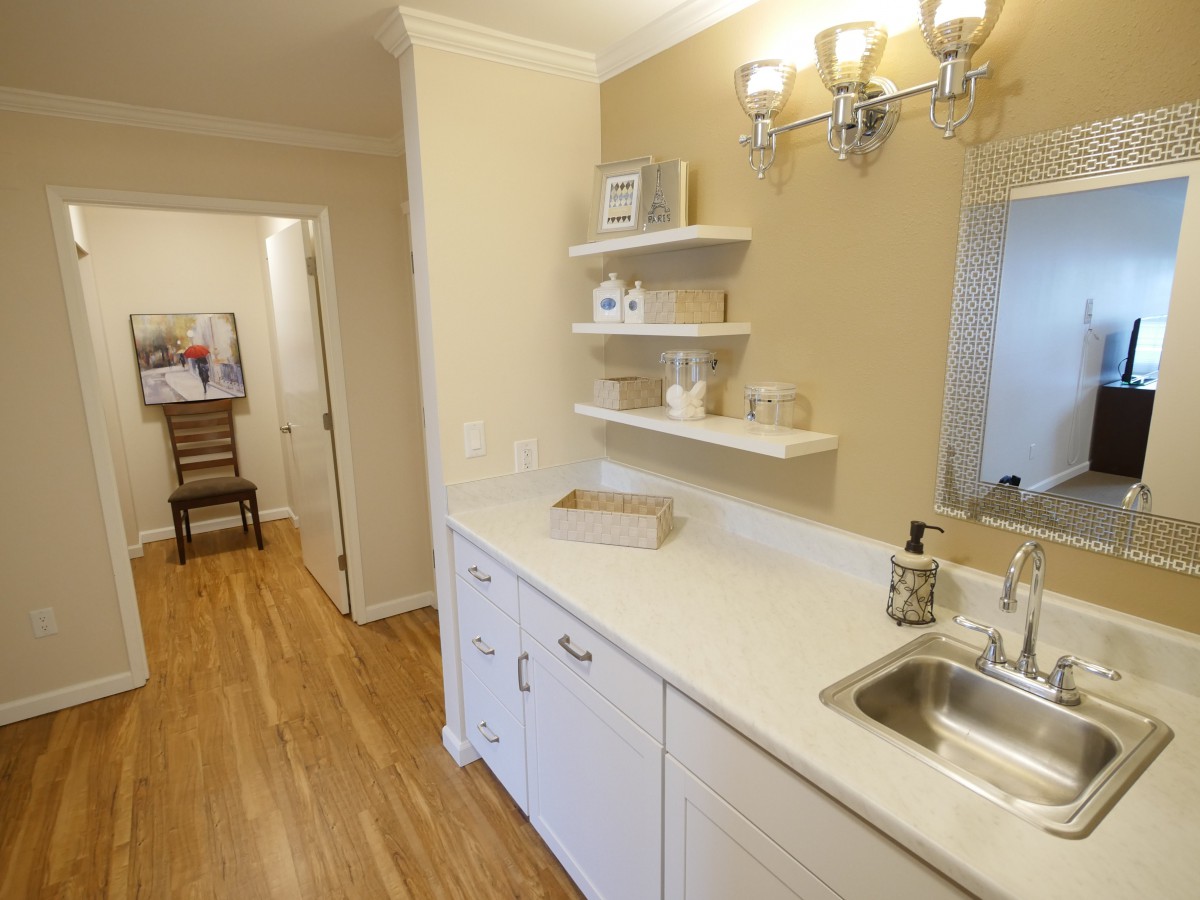A modern kitchen interior with a sleek countertop, open shelves, and wooden flooring.