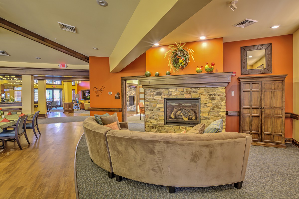 A cozy, modern living room featuring a curved couch and a stone fireplace.