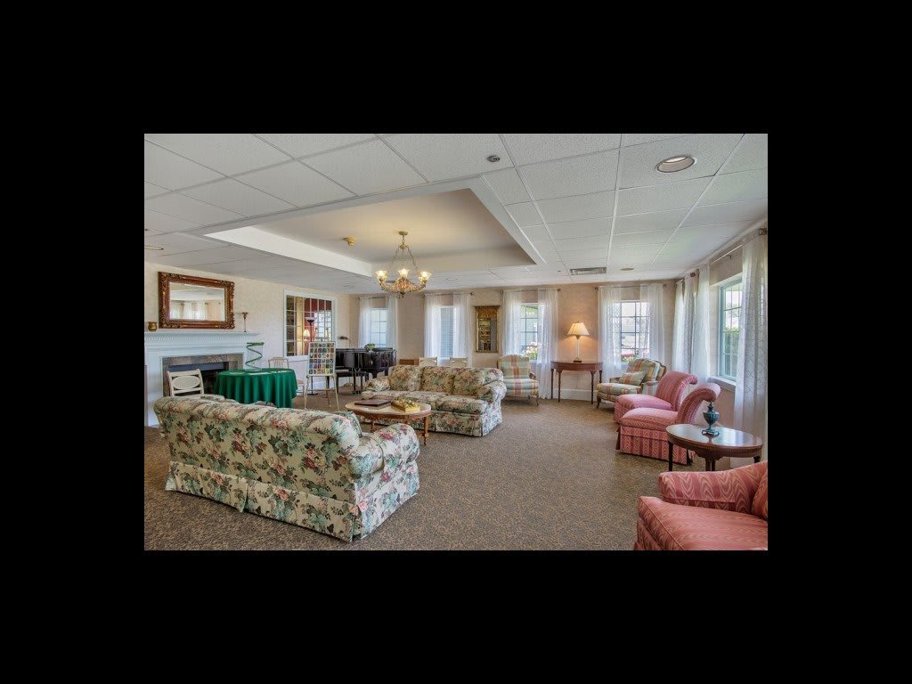 A spacious and elegantly furnished living room with multiple seating areas, featuring sofas and chairs arranged around a central coffee table.
