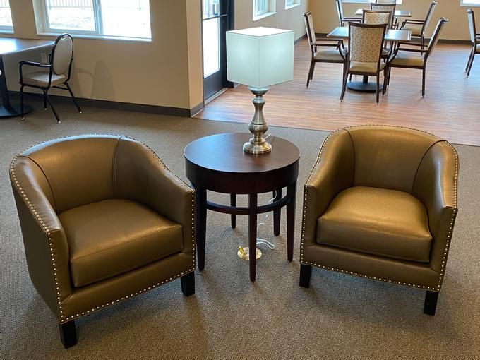 A cozy lounge area featuring two armchairs, a side table, and a lamp.