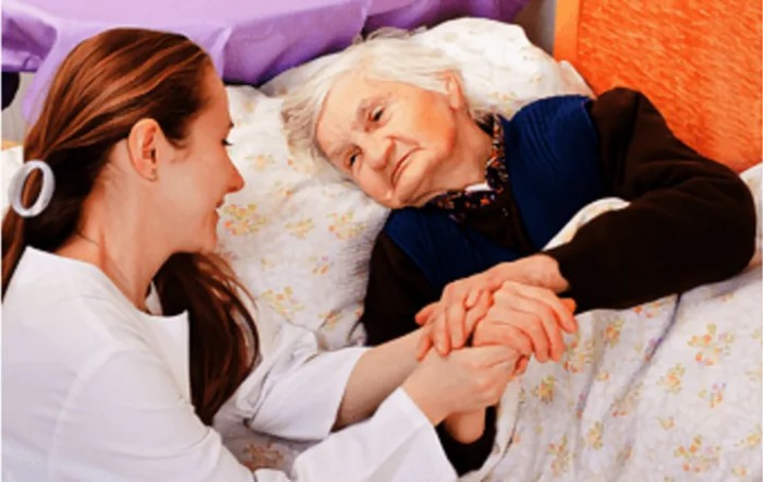 A nurse provides compassionate care to an elderly patient in a hospital bed.