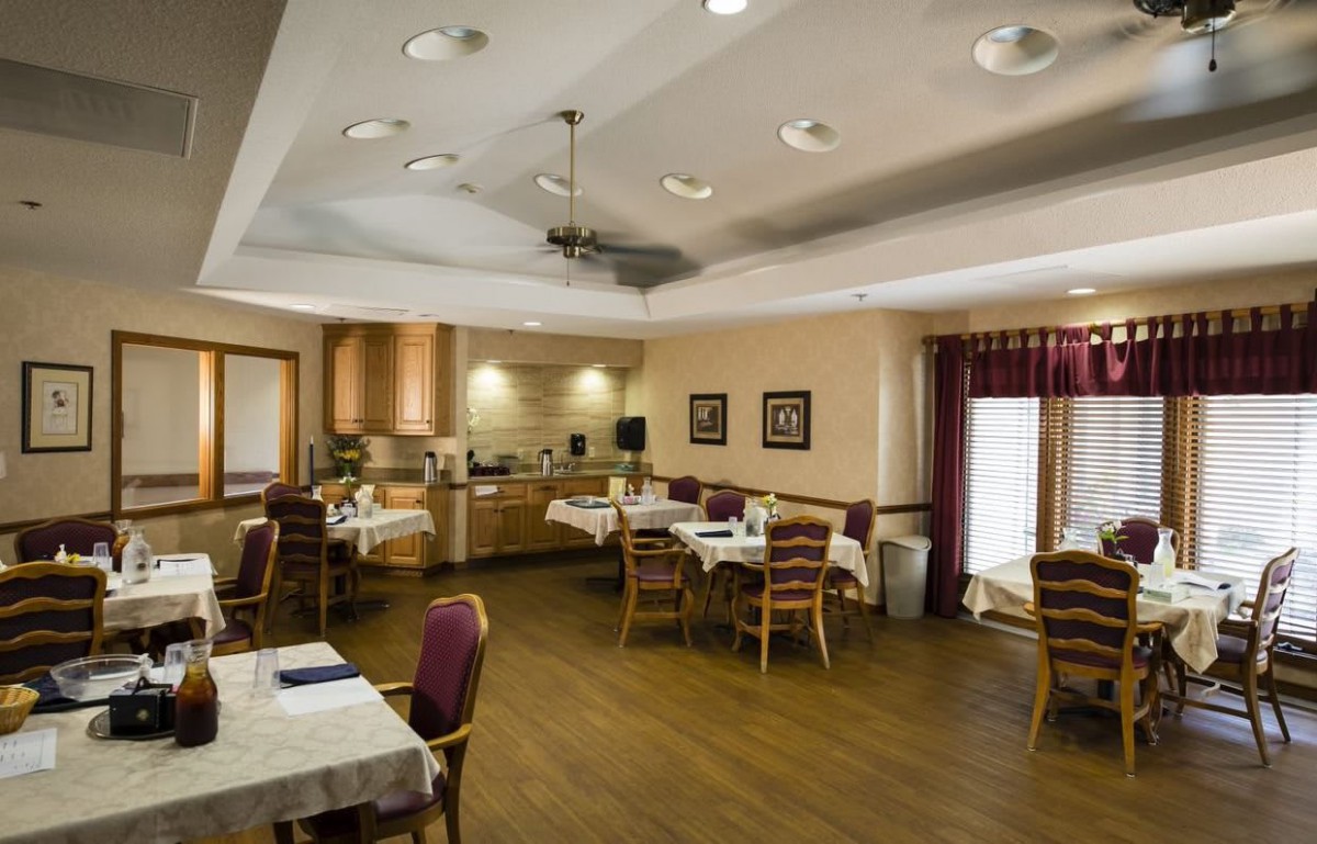 A cozy dining room with neatly arranged tables and chairs, featuring warm lighting and elegant decor.