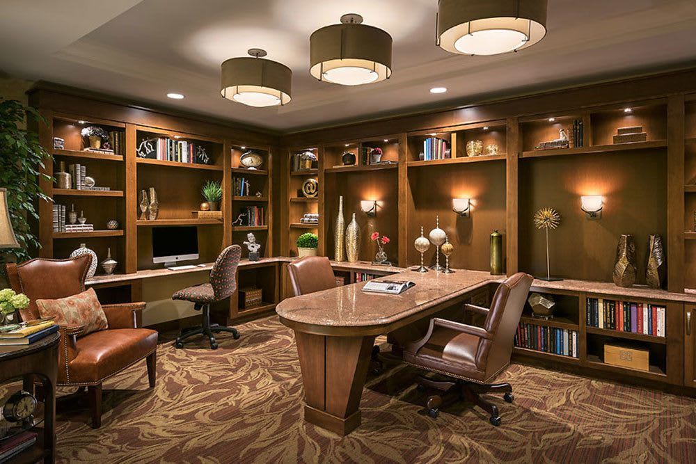 A well-designed office space with built-in bookshelves, comfortable seating, and warm lighting.
