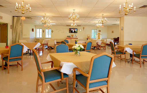 A well-lit dining area with tables and chairs set for guests, featuring elegant chandeliers.