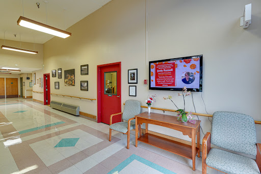 A spacious hallway featuring a television screen, decorative plants, and framed photographs on the walls.
