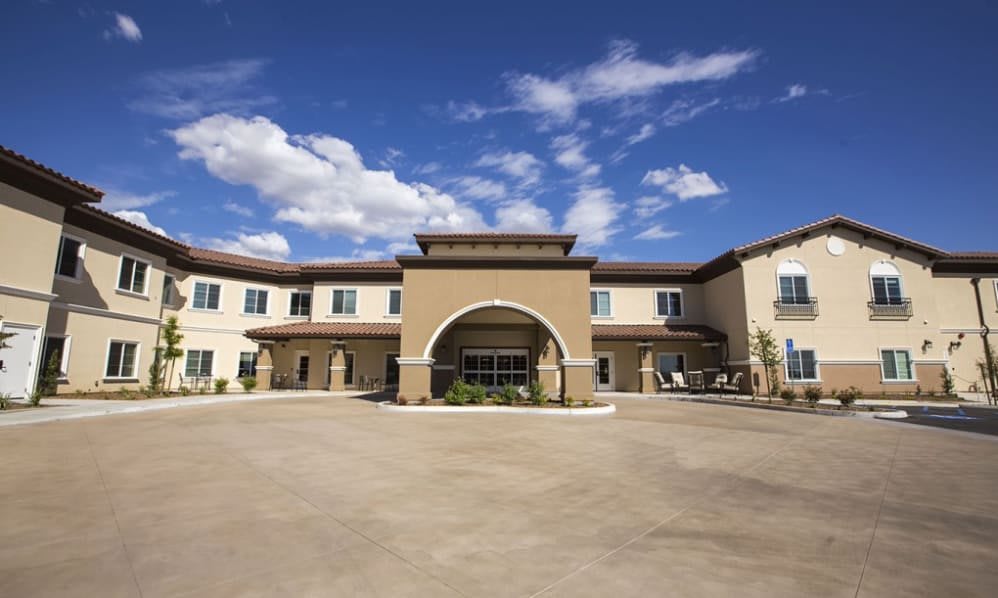 A two-story building with a grand entrance under a sunny sky with scattered clouds.