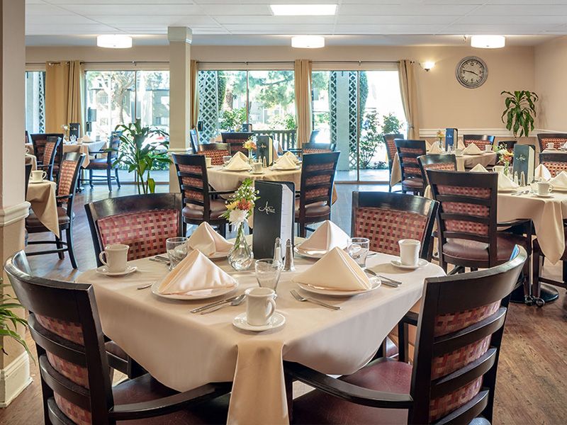 An elegantly set dining room with neatly arranged tables and chairs, ready for guests.