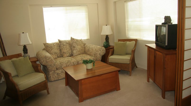 A cozy living room with a sofa, armchair, coffee table, and lamp.