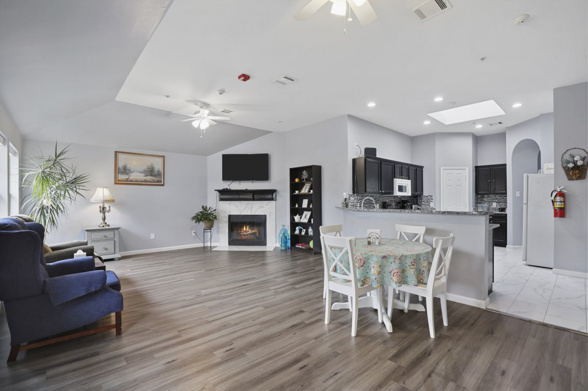 A modern open-concept living space featuring hardwood floors, a fireplace, and a dining area adjacent to the kitchen.