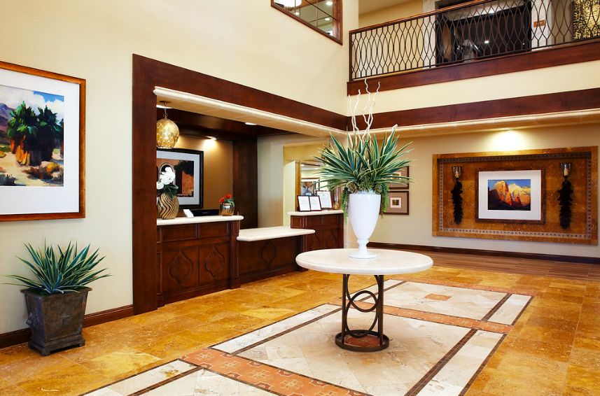 A stylish hotel lobby featuring a reception desk, decorative plants, and modern furniture.