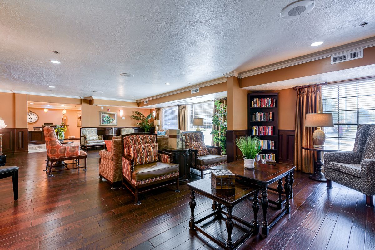 A cozy lounge area with comfortable seating, bookshelves, and plants.