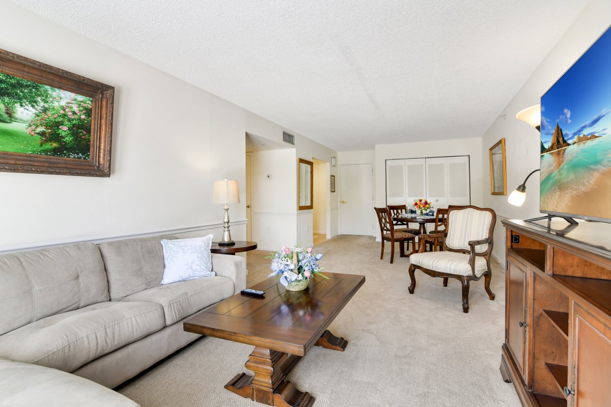 A cozy living room with a sofa and wooden furniture leading to a dining area.