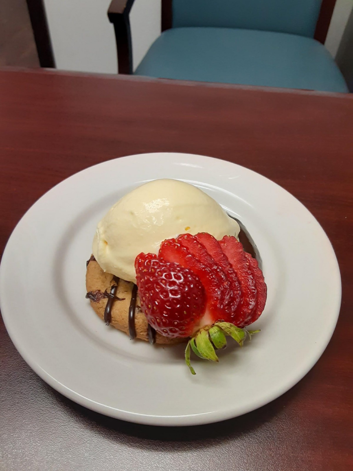A delicious dessert featuring a scoop of vanilla ice cream atop a cookie, garnished with fresh strawberry slices.
