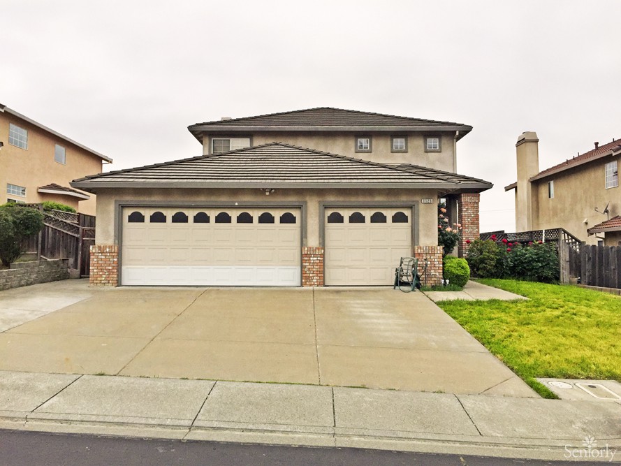 A suburban two-story house with a three-car garage and a well-maintained lawn.