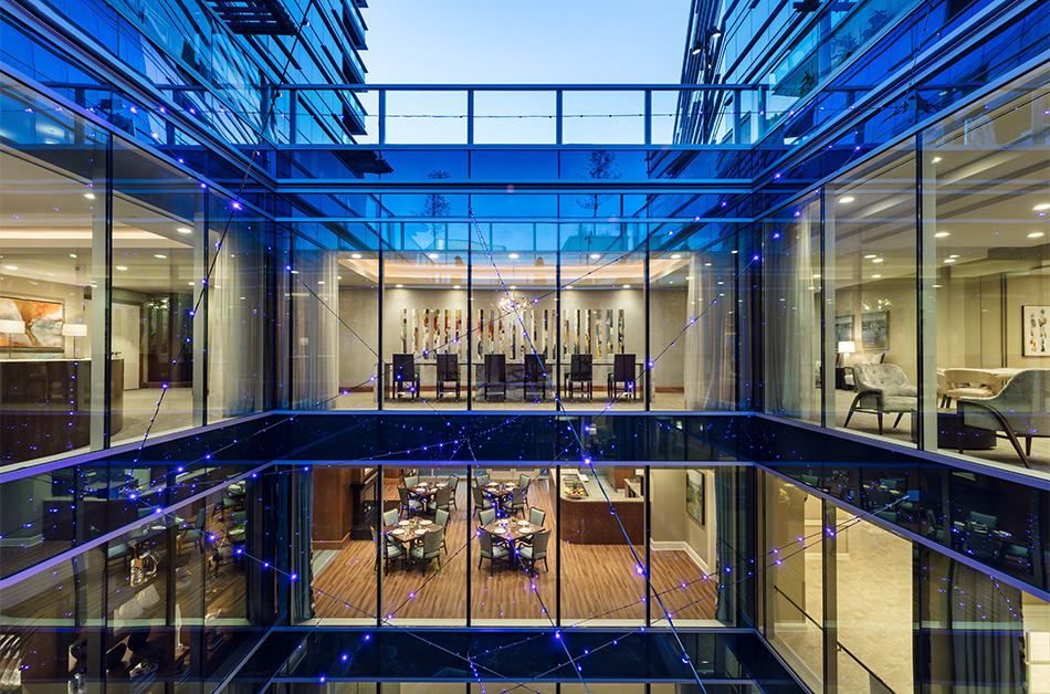 A modern office building with a glass facade showcasing an interior view of conference rooms in the evening.