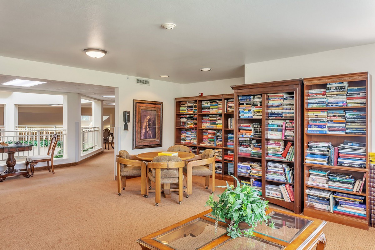 A cozy library reading area with bookshelves, a table, and chairs.