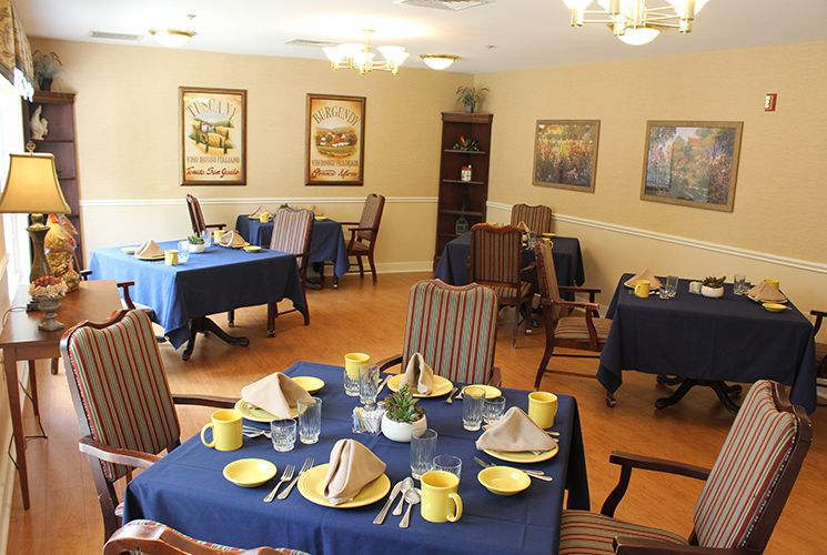 A neatly arranged dining room with blue tablecloths and yellow dishes.